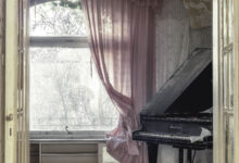 Verlassenes Zimmer mit Klavier und rosa Vorhängen.