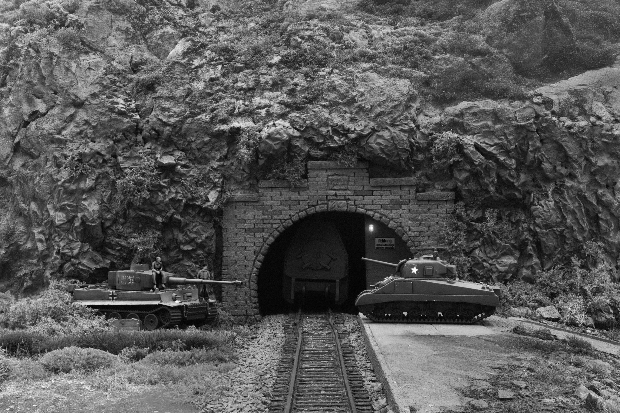 Diorama: Tiger- und Sherman-Panzer vor Gebirgstunnel mit Gleisen.